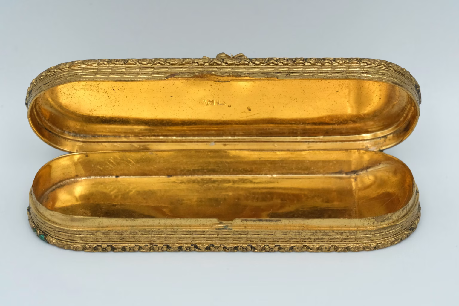 A trinket box from the 19th century open, with a gold lustre, in front of a gray background
