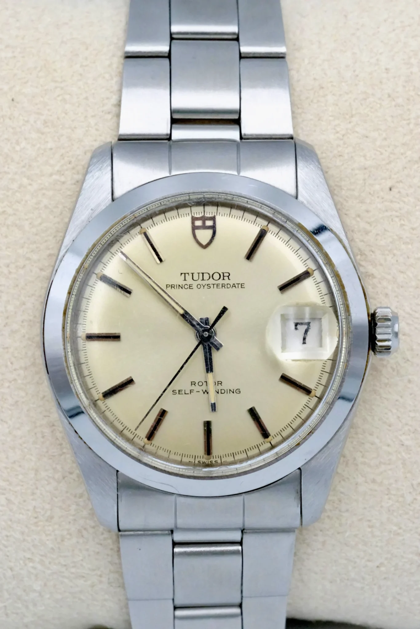 A silver watch with an oyster dial sits atop a jewlery display piece