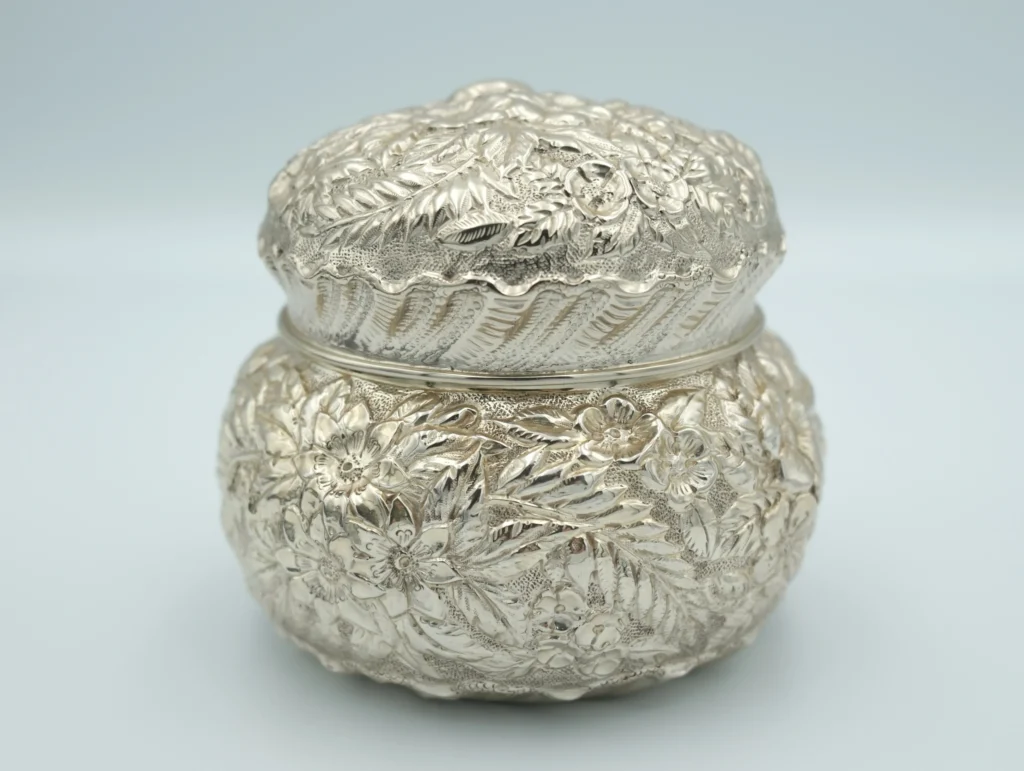 A silver repousse with textured sterling silver sits in front of a gray background