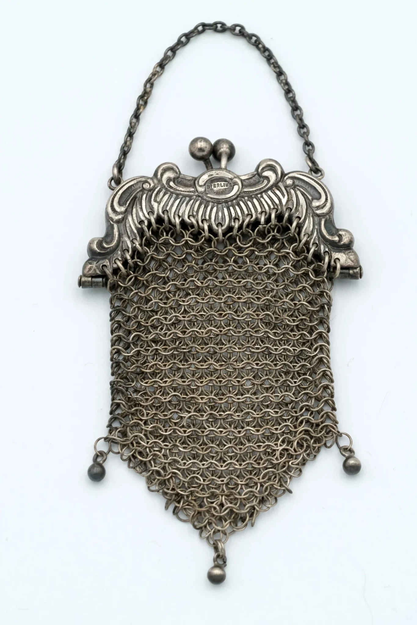 A chainmail mesh coin purse ornate frame sterling silver sitting atop a gray background