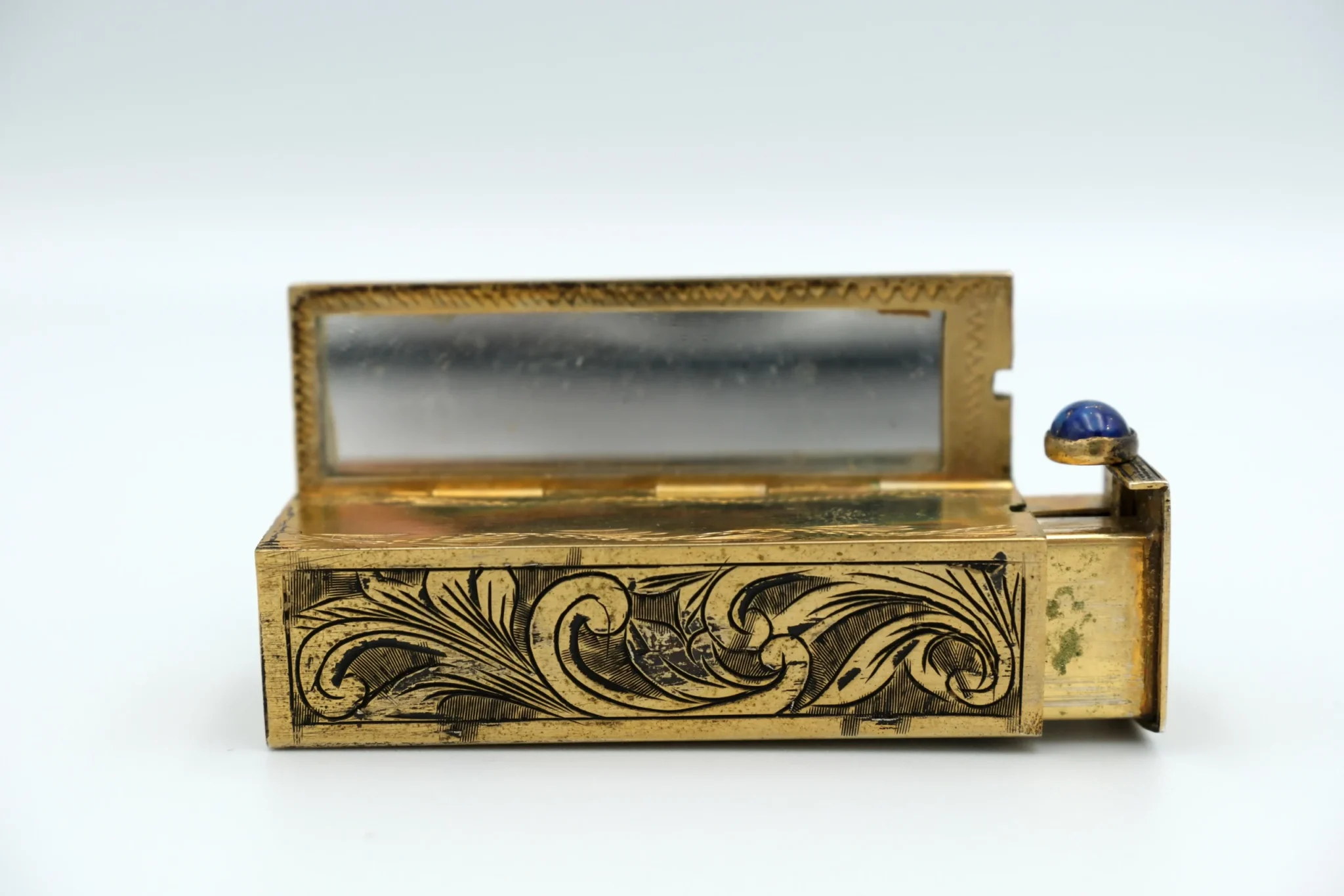 A gold and blue mirror italian silver blue guilloche enamel from the early 20th century sitting a top a gray background
